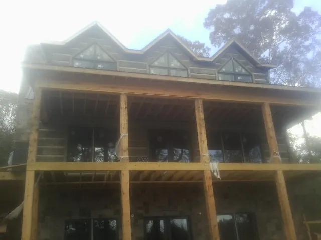 Dormers and porch framing on a large log home under construction — Roof Coating work by our crew in Luverne